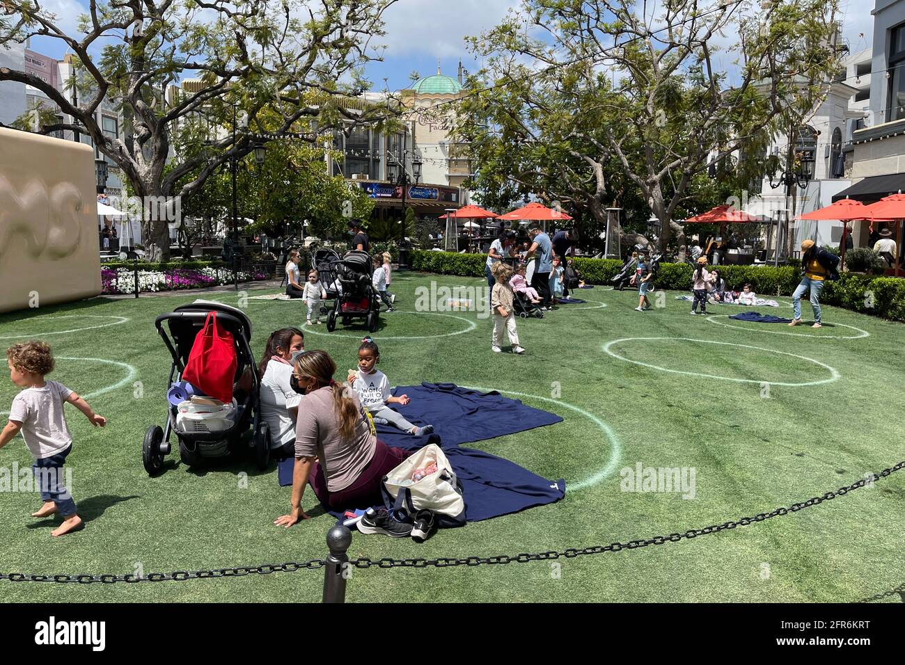 Le persone si rilassano in circoli di allontanamento sociale sul prato del centro commerciale Grove, giovedì 20 maggio 2021, a Los Angeles. Foto Stock