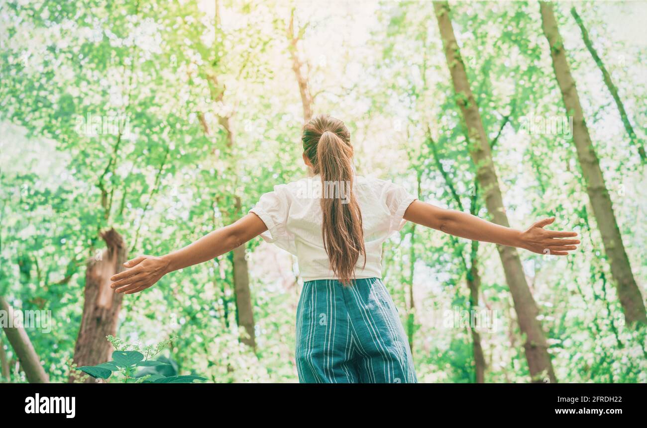 Abbigliamento sostenibile eco-friendly moda donna sentirsi libero con le braccia aperte in boschi foresta felice di breare aria pulita. Ragazza turistica di viaggio che cammina dentro Foto Stock