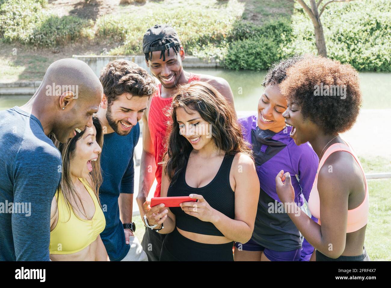 Gruppo di runner che guarda qualcosa di molto divertente su un cellulare. Foto Stock