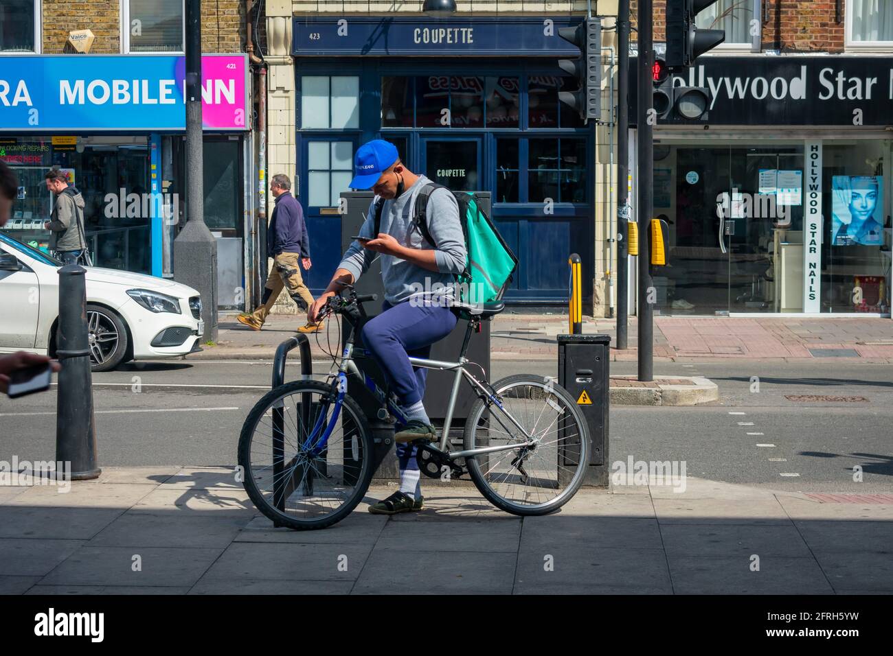 Londra. UK- 05.18.2021: Un giovane uomo che lavora come pilota domestico indipendente di consegna per l'azienda in linea di ordinazione di alimento Deliveroo. Foto Stock