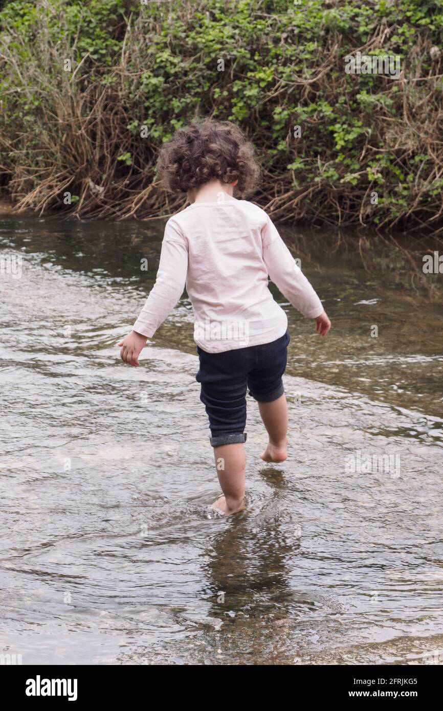 Giovane bambina che gioca all'aperto, sola in natura Foto Stock