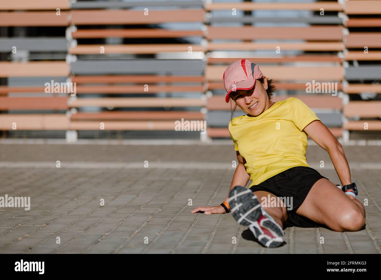 Giovane donna che fa stretching dopo la corsa all'aperto. Ragazza che si esercita con la città paesaggio sullo sfondo. Ragazza latina Foto Stock