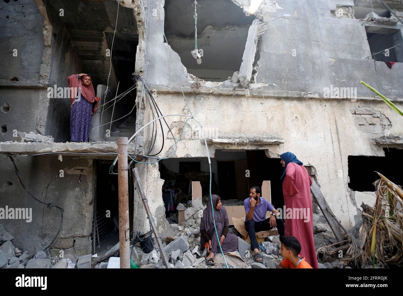I palestinesi si siedono sui detriti dopo il ritorno alla loro casa distrutta dopo la tregua di Israele-Hamas, a Beit Hanoun, nella striscia di Gaza settentrionale, il 21 maggio 2021. REUTERS/Mohammed Salem Foto Stock