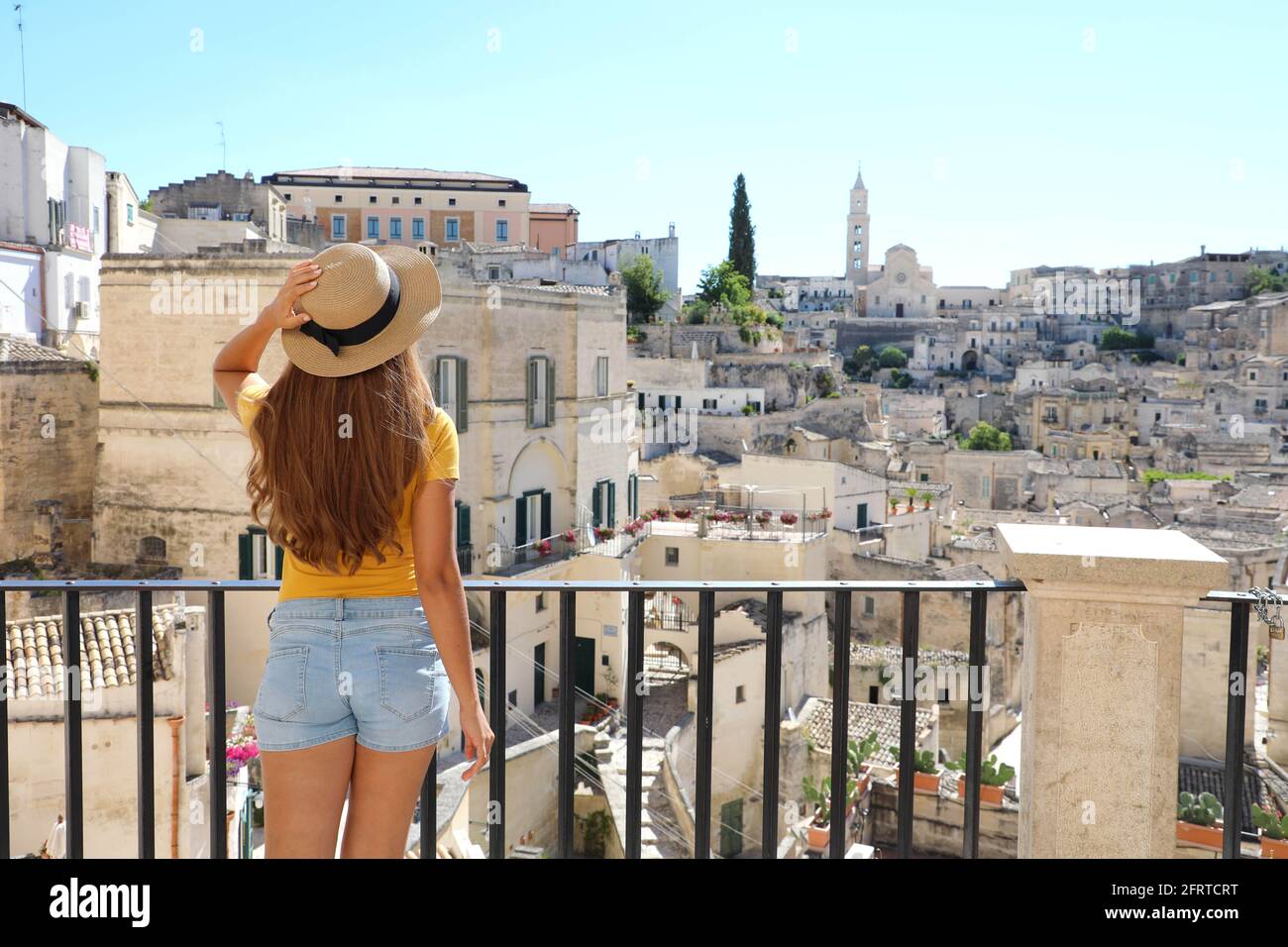 Bella ragazza turistica in piedi sul balcone e guardando il paesaggio della città del sud europa con antiche rovine di Matera, italia Foto Stock