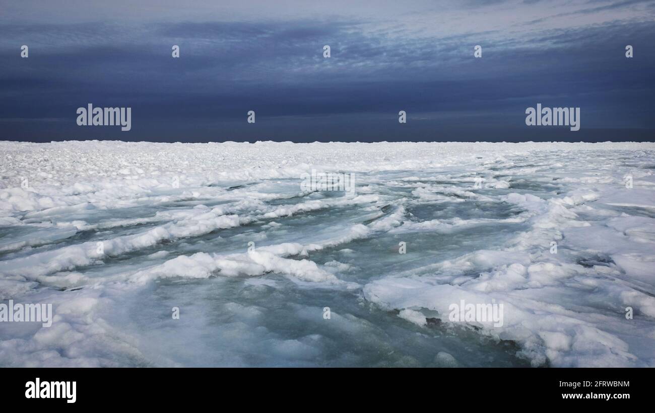 Ghiacciai innevati in una soleggiata giornata invernale in riva al mare. Tutto è congelato, il cielo è molto blu. Atmosfera drammatica. Foto Stock