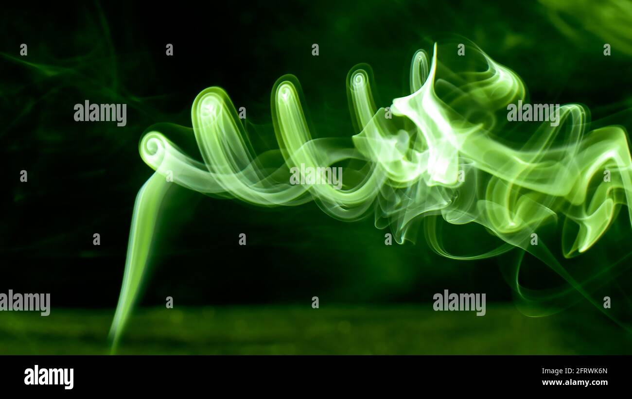 Il fumo luminescente verde brillante ruota in un vortice mistico. Fantasia e fotografia magica. Ottima foto per lo sfondo del computer o il desktop del telefono. Foto Stock