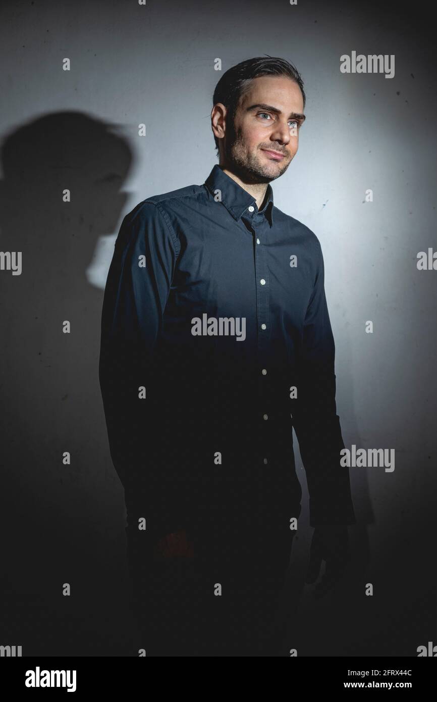 Un influencer, artista e musicista, vestito con camicia nera, posa per la  macchina fotografica in uno dei suoi tiri fotografici per i social network,  in una b oscura Foto stock - Alamy