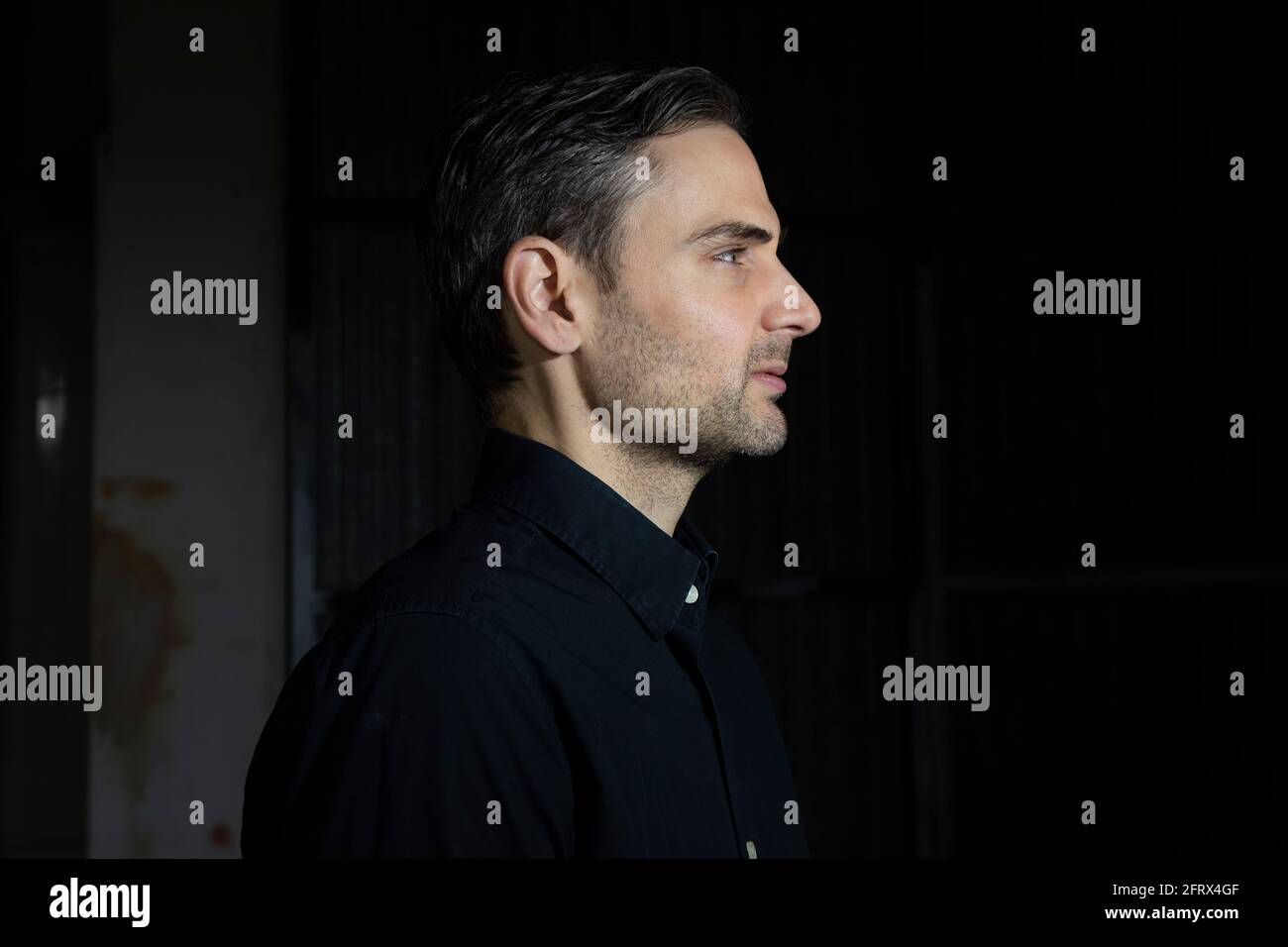 Un influencer, artista e musicista, vestito con camicia nera, pone per la  fotocamera in uno dei suoi rapporti fotografici per i social network, in un  bac scuro Foto stock - Alamy