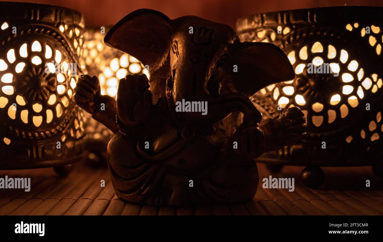 Figura Golden ganesha con calda luce a candela. Primo piano di elefante dorato con candele orientali. Concetto buddista Foto Stock