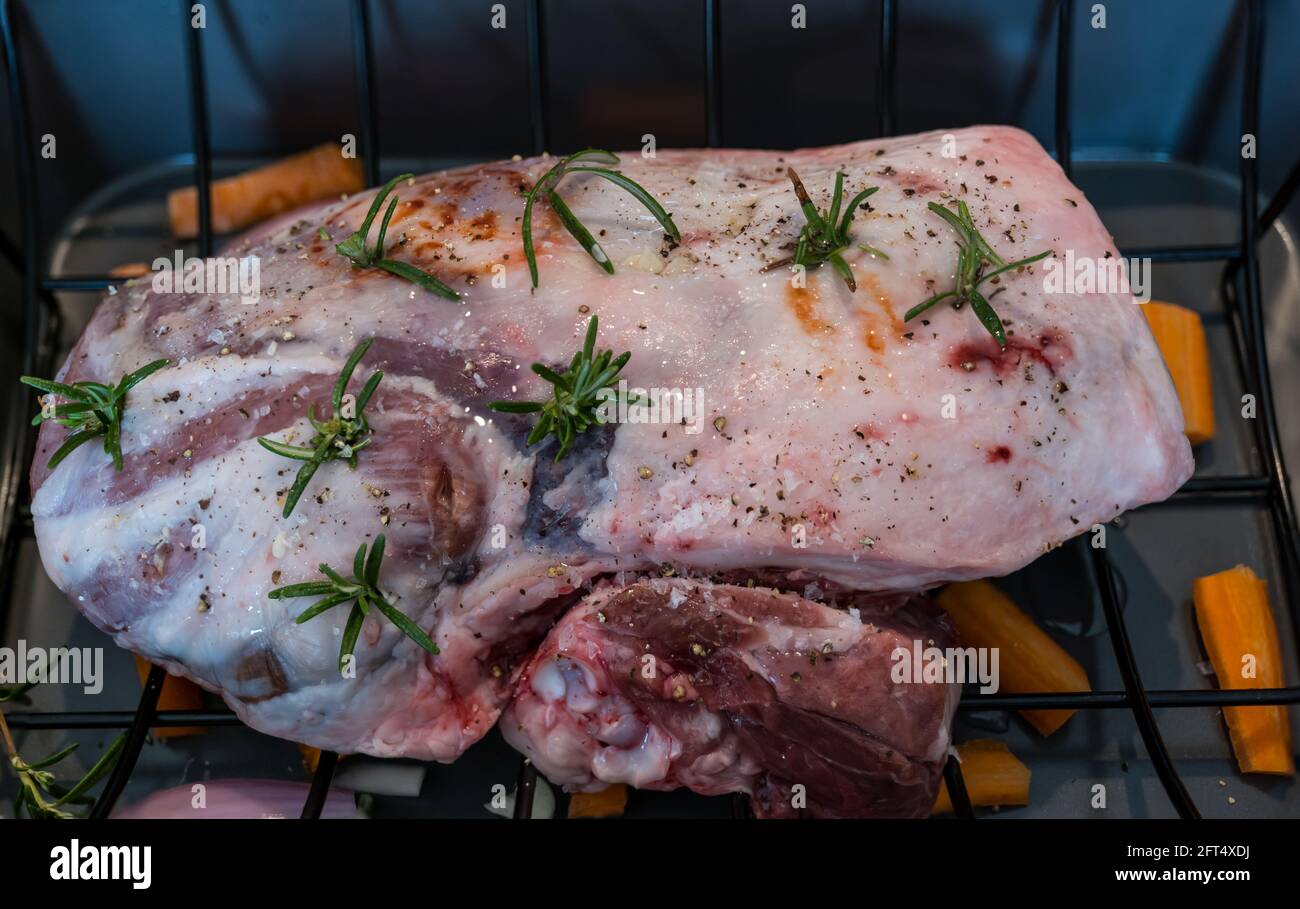 Briggs Shetland gamba primaverile di agnello e groppa in tostatura vassoio preparato per la cottura con sprigg di rosmarino e condimento Foto Stock