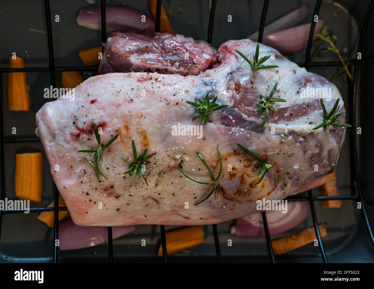 Briggs Shetland gamba primaverile di agnello e groppa in tostatura vassoio preparato per la cottura con sprigg di rosmarino e condimento Foto Stock