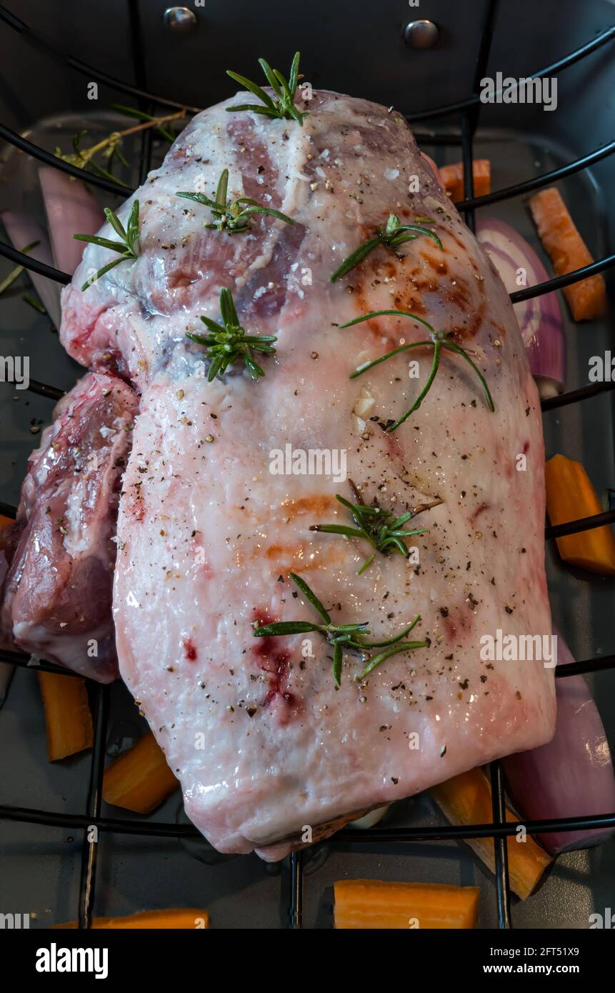 Briggs Shetland gamba primaverile di agnello e groppa in tostatura vassoio preparato per la cottura con sprigg di rosmarino e condimento Foto Stock