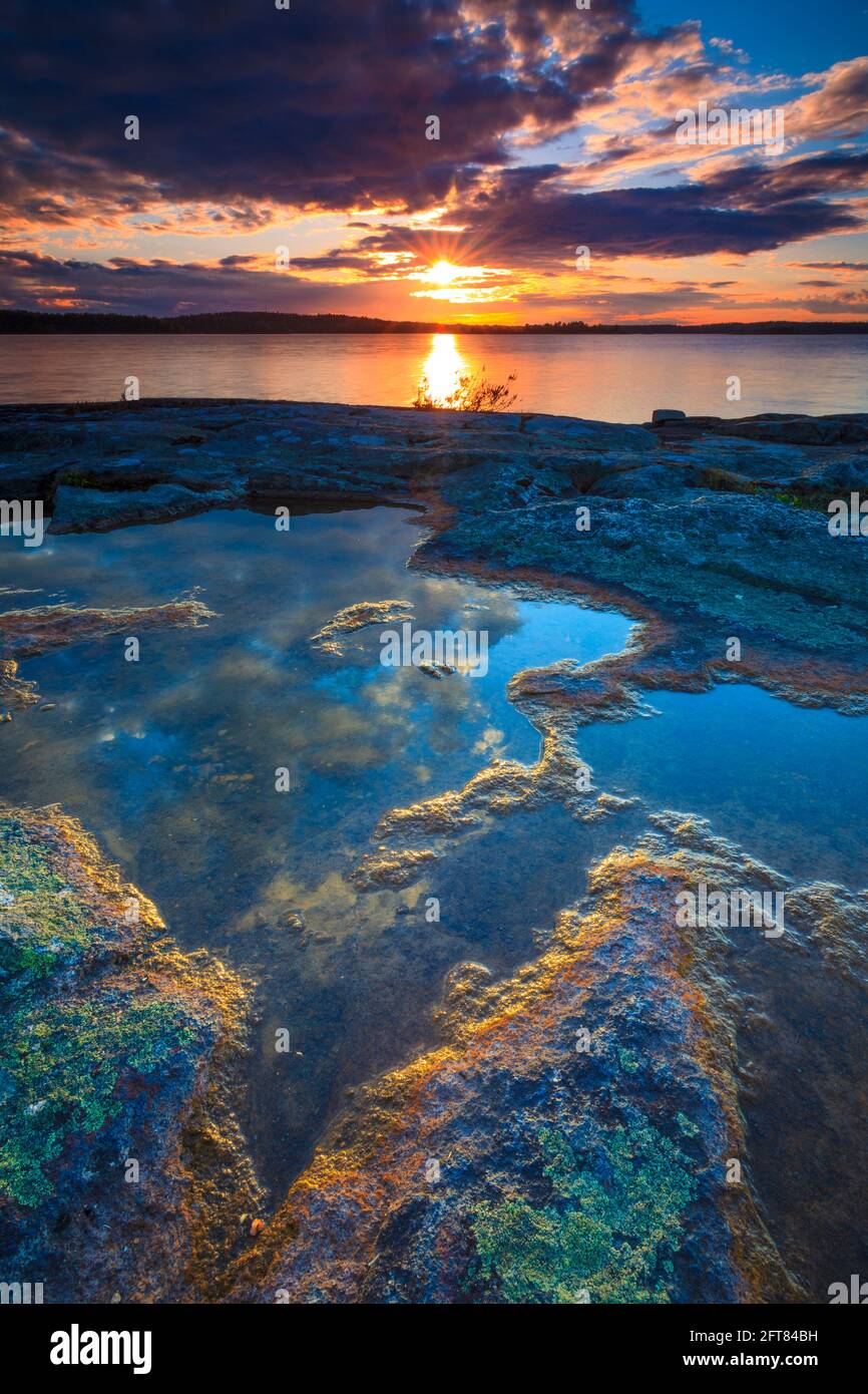Tramonto suggestivo e colorato con luce dell'ora d'oro su rocce colorate e piccole piscine sul lago di Vansjø a Østfold, Norvegia, Scandinavia. Foto Stock