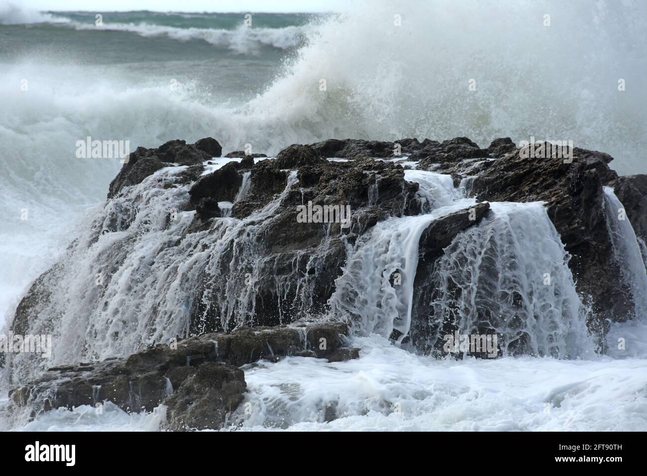 Rottura dell'onda sulla roccia Foto Stock
