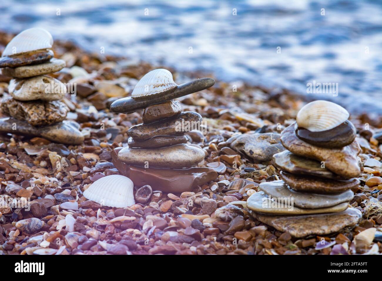 Tre torretta di ciottoli di mare e conchiglia bianca sulla parte superiore. Pietre di mare sulla spiaggia. Estate stagione di vacanza a località di mare immagine. Foto Stock