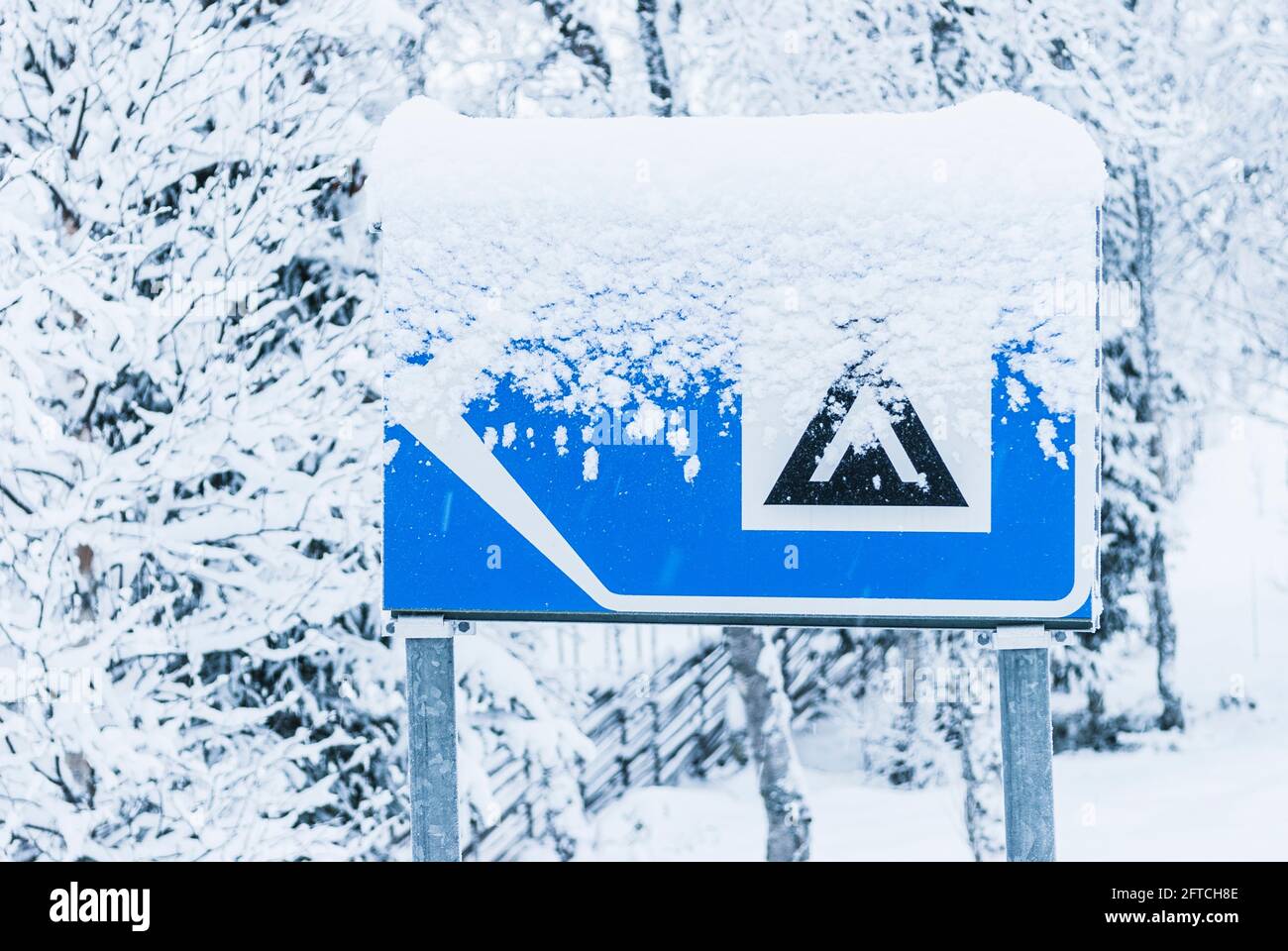 Cartello campeggio innevato su strada Foto Stock