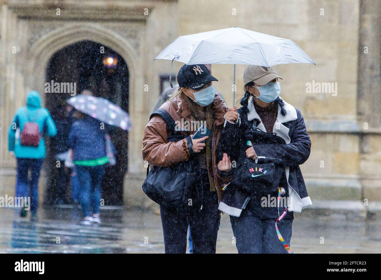 Bath, Somerset, Regno Unito. 21 Maggio 2021. Due donne che riparano sotto un ombrello sono raffigurate all'esterno dell'abbazia di Bath mentre le forti docce a pioggia fanno la loro strada attraverso il Regno Unito. Credit: Lynchpics/Alamy Live News Foto Stock