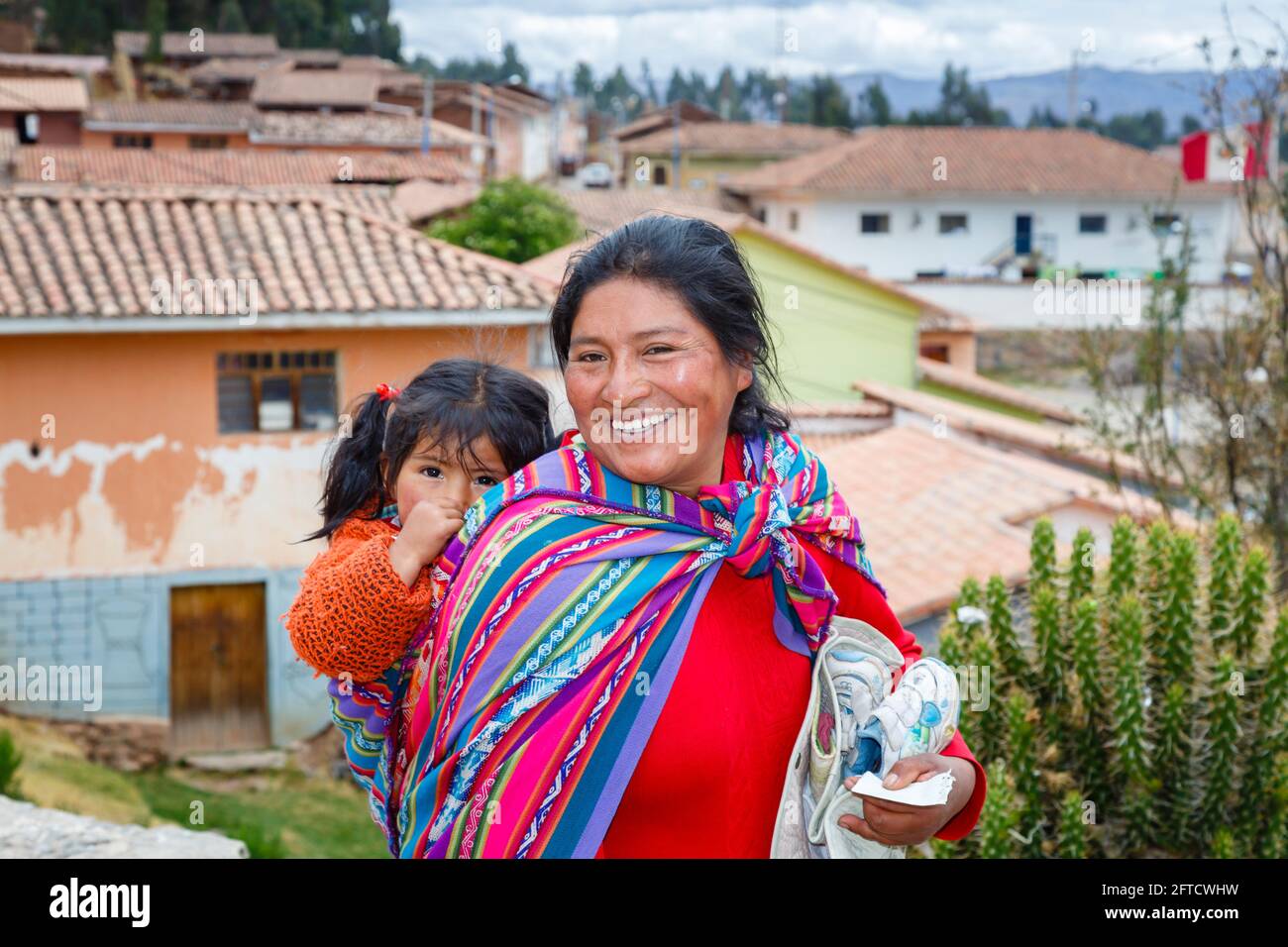Una donna locale di Quechua porta la figlia in una papiosa di scialle a  Chinchero, un villaggio andino rustico nella Valle Sacra, Urubamba, Cusco,  Perù Foto stock - Alamy