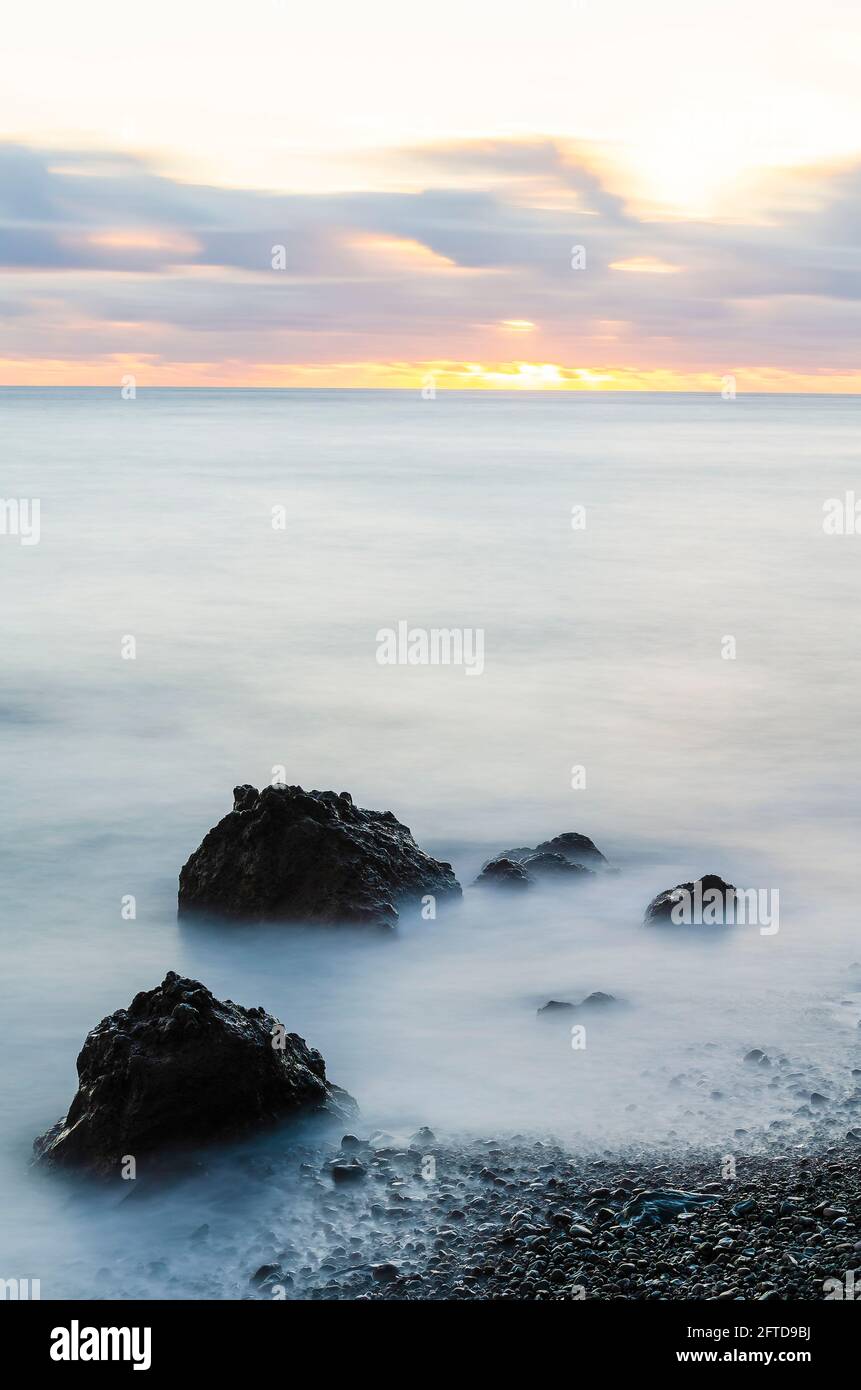Formazioni rocciose in mare al tramonto Foto Stock