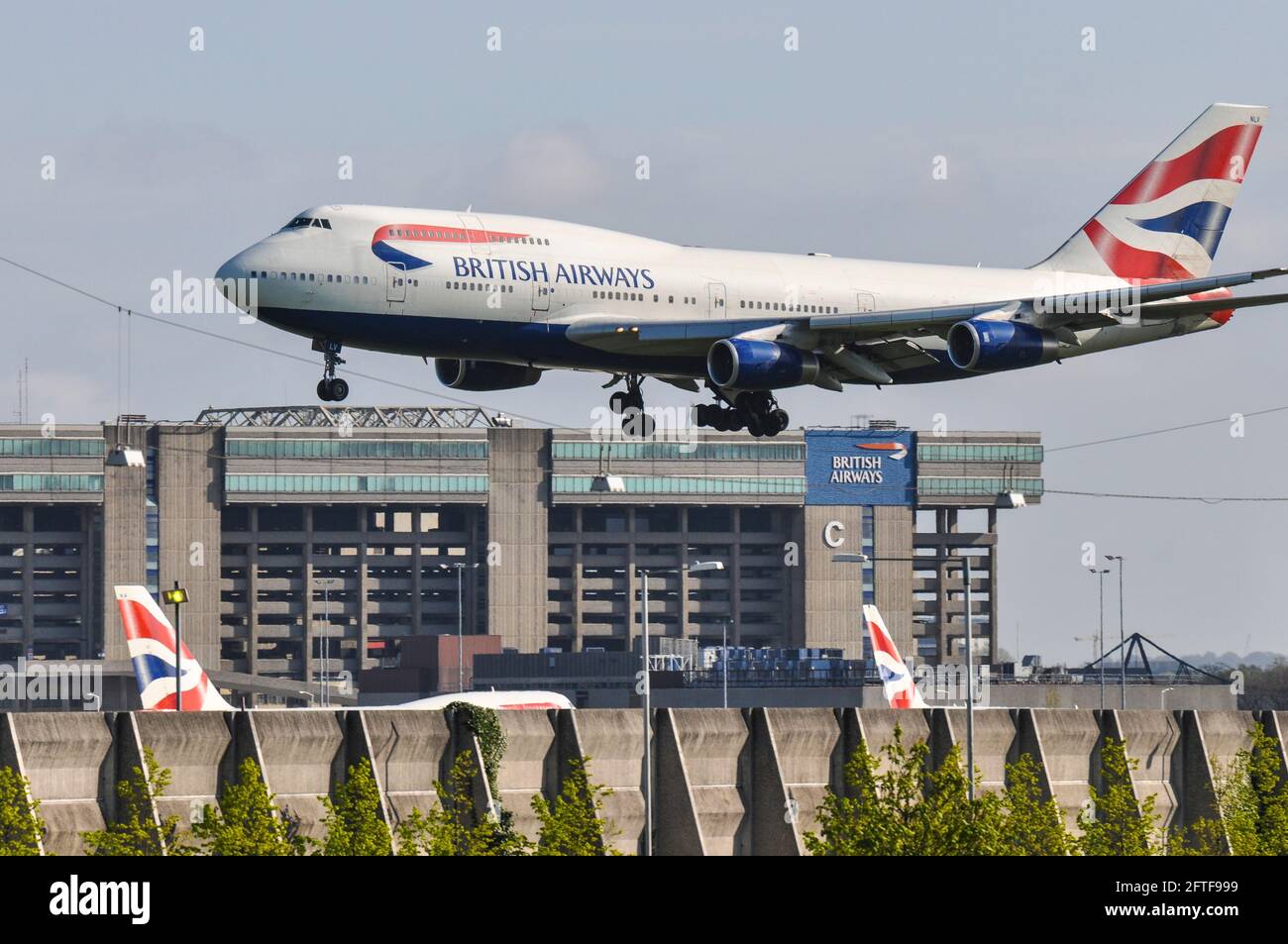 British Airways Boeing 747 Jumbo Jet Plane G-BNLV atterrando all'aeroporto Heathrow di Londra, Regno Unito, sopra l'hangar della base di manutenzione della British Airways Foto Stock