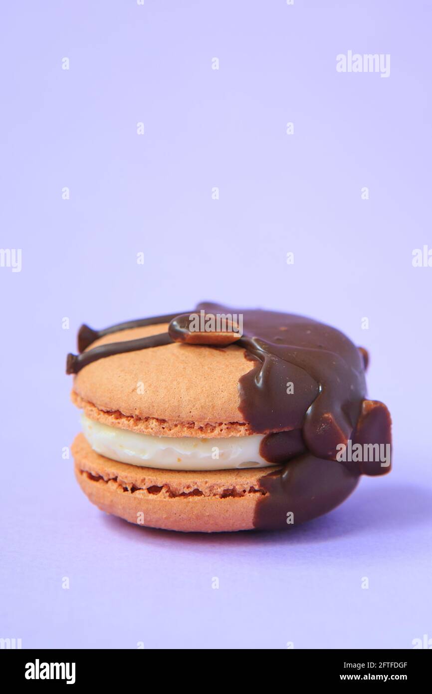 Cioccolato Cake macaron o macaroon su sfondo viola. Biscotti colorati alle mandorle. Primo piano sulla torta di macaroon francese. Macaroni su sfondo colorato Foto Stock