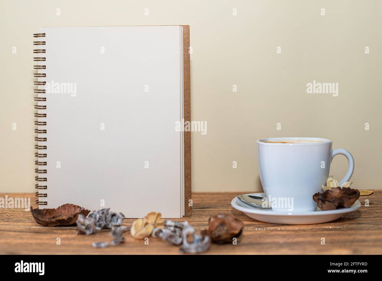 Apri il quaderno a spirale con un foglio bianco, una tazza di caffè accanto e decorazioni da tavolo Foto Stock