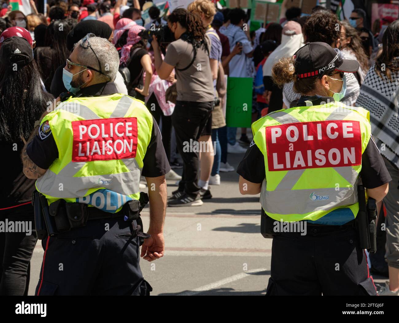 Ottawa, Canada. 15 maggio 2021. Collegamento della polizia con giubbotto ad alta visibilità tra la folla per protesta di strada Foto Stock