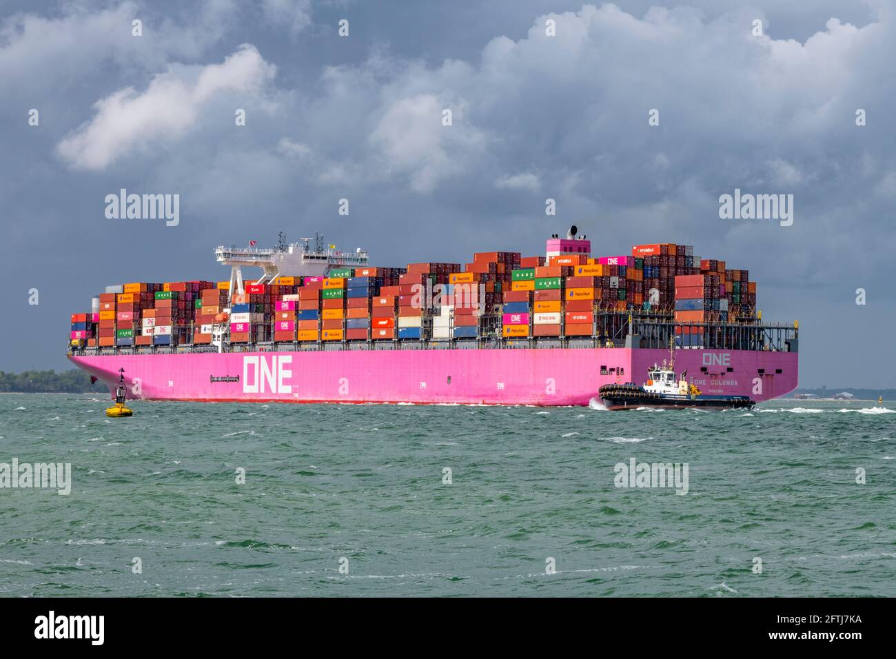 una grande nave containere una columbia che trasporta via mare contenitori che si avvicina al porto di southampton ormeggia con un rimorchiatore per l'assistenza nel solent. Foto Stock