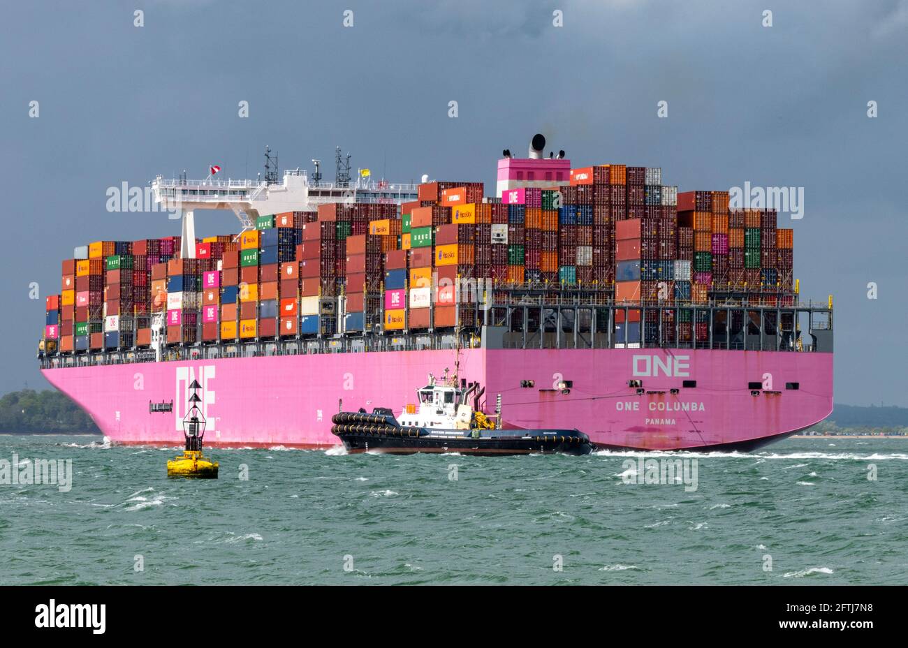 una grande nave containere una columbia che trasporta via mare contenitori che si avvicina al porto di southampton ormeggia con un rimorchiatore per l'assistenza nel solent. Foto Stock