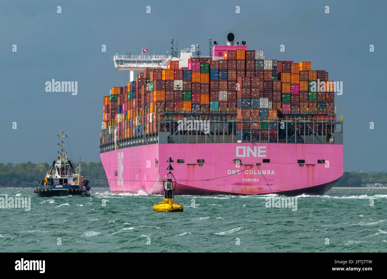 una grande nave containere una columbia che trasporta via mare contenitori che si avvicina al porto di southampton ormeggia con un rimorchiatore per l'assistenza nel solent. Foto Stock
