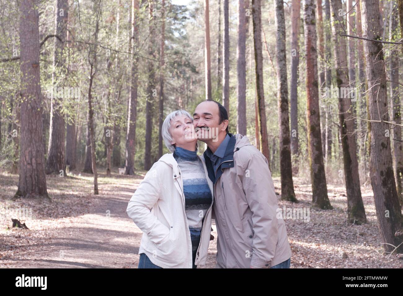 Anziana coppia interracial in vestiti casual che si infrangono in un parco di foresta di primavera. Foto Stock