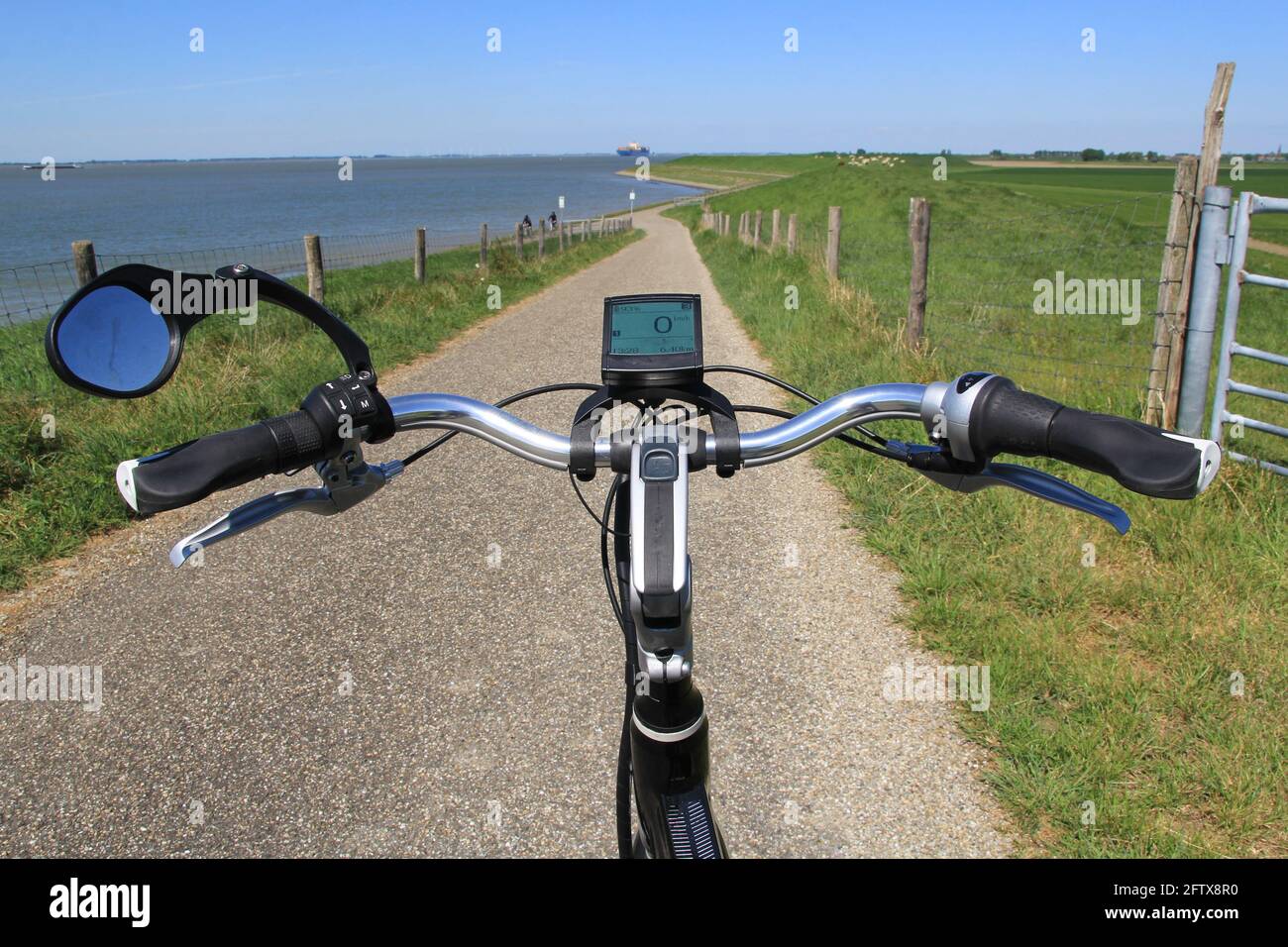 una bicicletta elettrica si trova su una strada in una diga che attraversa il mare di westerschelde in zeeland, paesi bassi in primavera Foto Stock