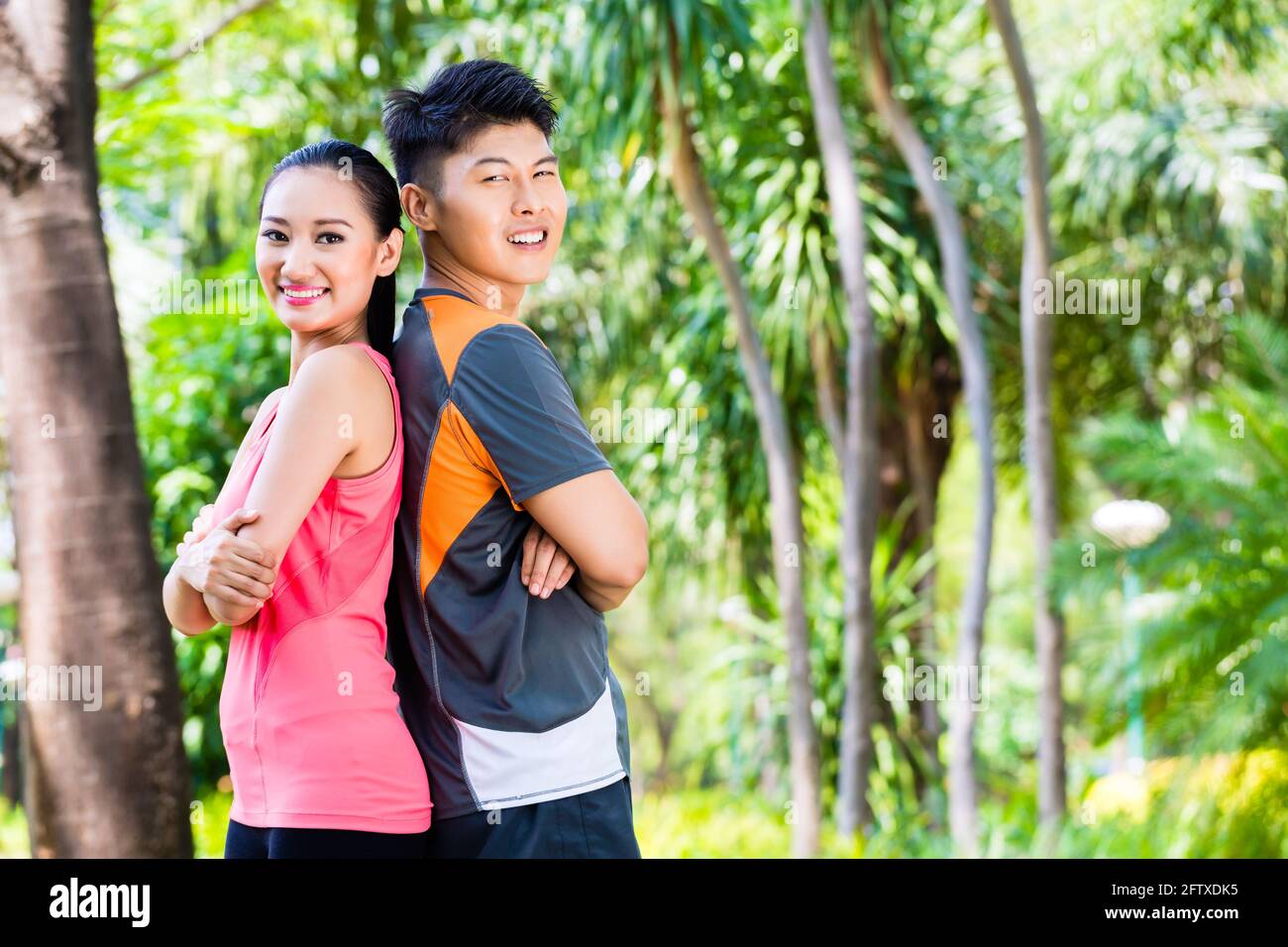 Cinese asiatico l uomo e la donna si prendono una pausa dopo la idoneità a fare jogging nel parco della città Foto Stock