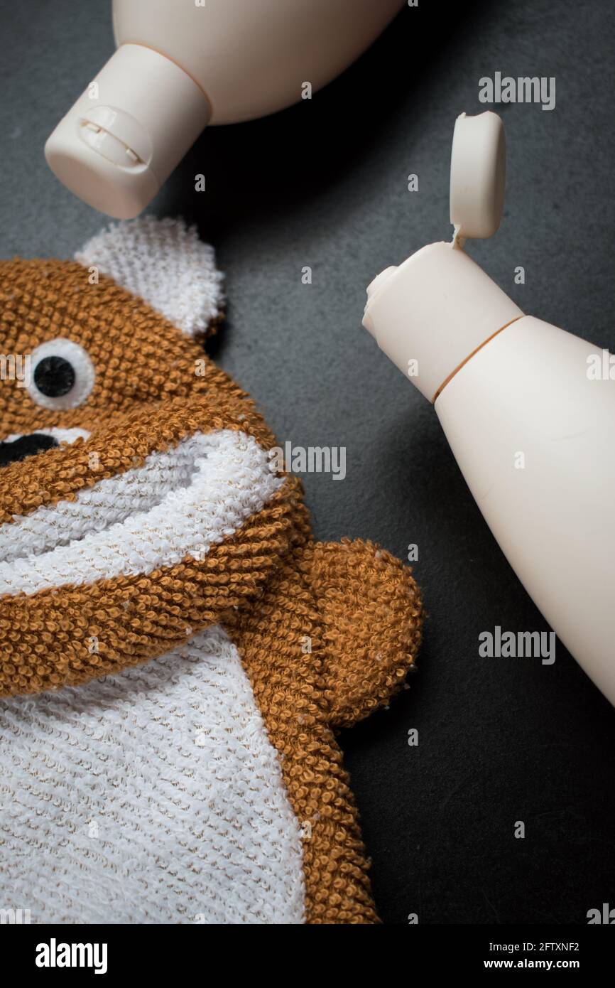 Asciugamano a forma di orso con alcune bottiglie di plastica bianca su un tavolo di legno nero Foto Stock