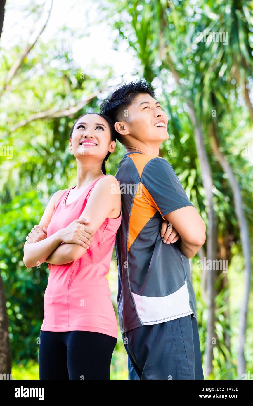 Cinese asiatico l uomo e la donna si prendono una pausa dopo la idoneità a fare jogging nel parco della città Foto Stock