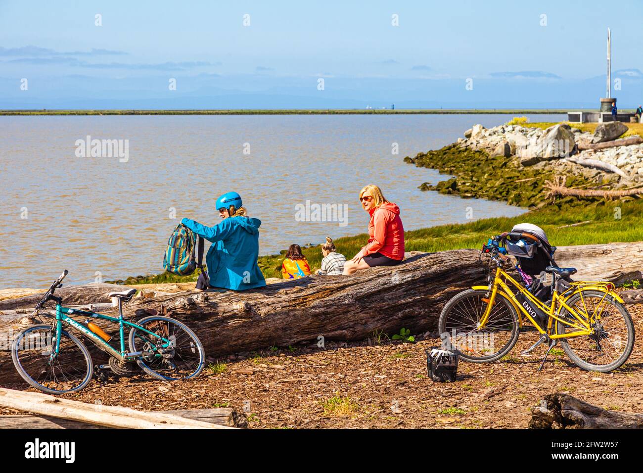 Due amici in bicicletta seduti su un driftwood log a Gary Point Park a Steveston British Columbia Canada Foto Stock