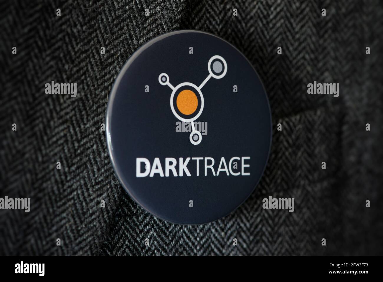 Un badge a bottone con il logo della società di cyber sicurezza Darktrace,  fissato a una giacca tuta Foto stock - Alamy