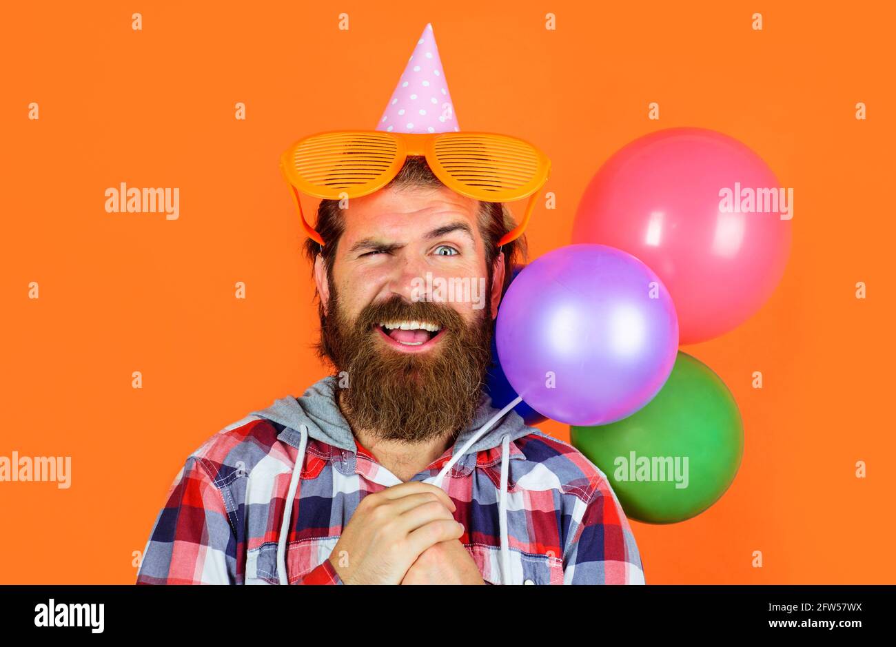 Buon compleanno. Felice uomo bearded con palloncini e bicchieri Party. Vacanze e festeggiamenti. Foto Stock