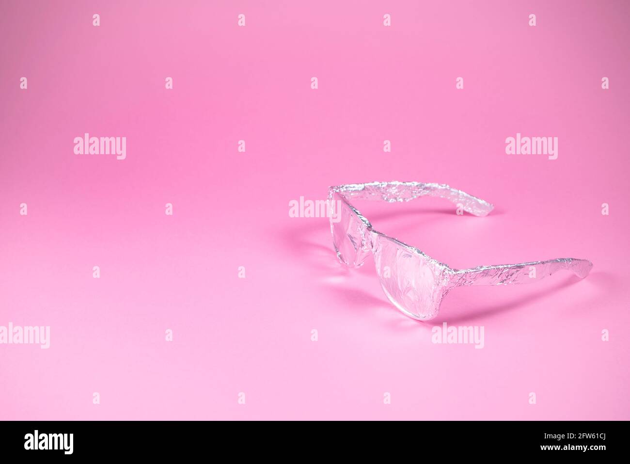 Occhiali da sole retrò avvolti in lamina di alluminio su sfondo rosa alla moda. Aspetto futuristico. Concetto estivo astratto minimo. Con spazio per la copia. Foto Stock