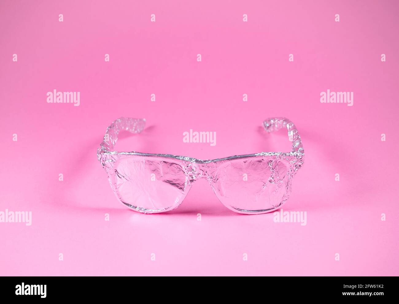 Occhiali da sole retrò avvolti in lamina di alluminio su sfondo rosa alla moda. Aspetto futuristico. Concetto estivo astratto minimo. Con spazio per la copia. Foto Stock
