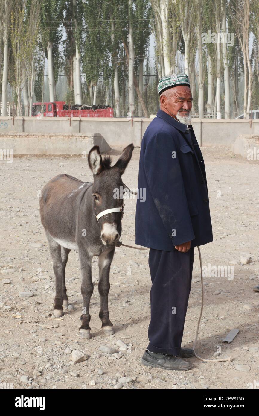 Un vecchio con un asino alla fiera animale Kashgar, Xinkiang, Repubblica popolare Cinese, 2019 Foto Stock