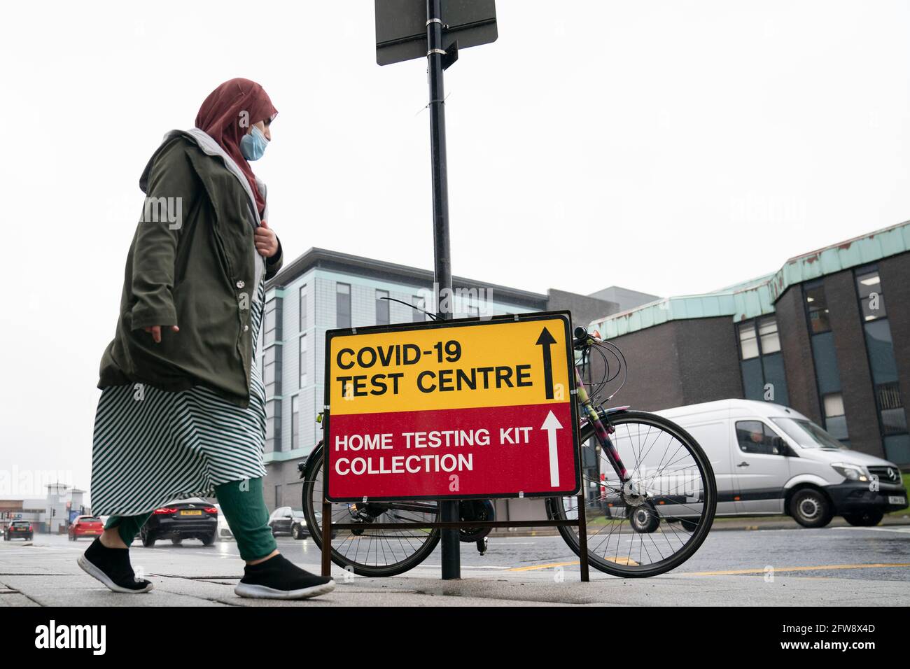 Bolton, Gran Bretagna. 21 Maggio 2021. Una donna oltrepassa un cartello per un centro di test COVID-19 a Bolton, Gran Bretagna, il 21 maggio 2021. Altre 2,829 persone in Gran Bretagna hanno dato risultati positivi per COVID-19, portando il numero totale di casi di coronavirus nel paese a 4,457,923, secondo i dati ufficiali rilasciati venerdì. Credit: Jon Super/Xinhua/Alamy Live News Foto Stock