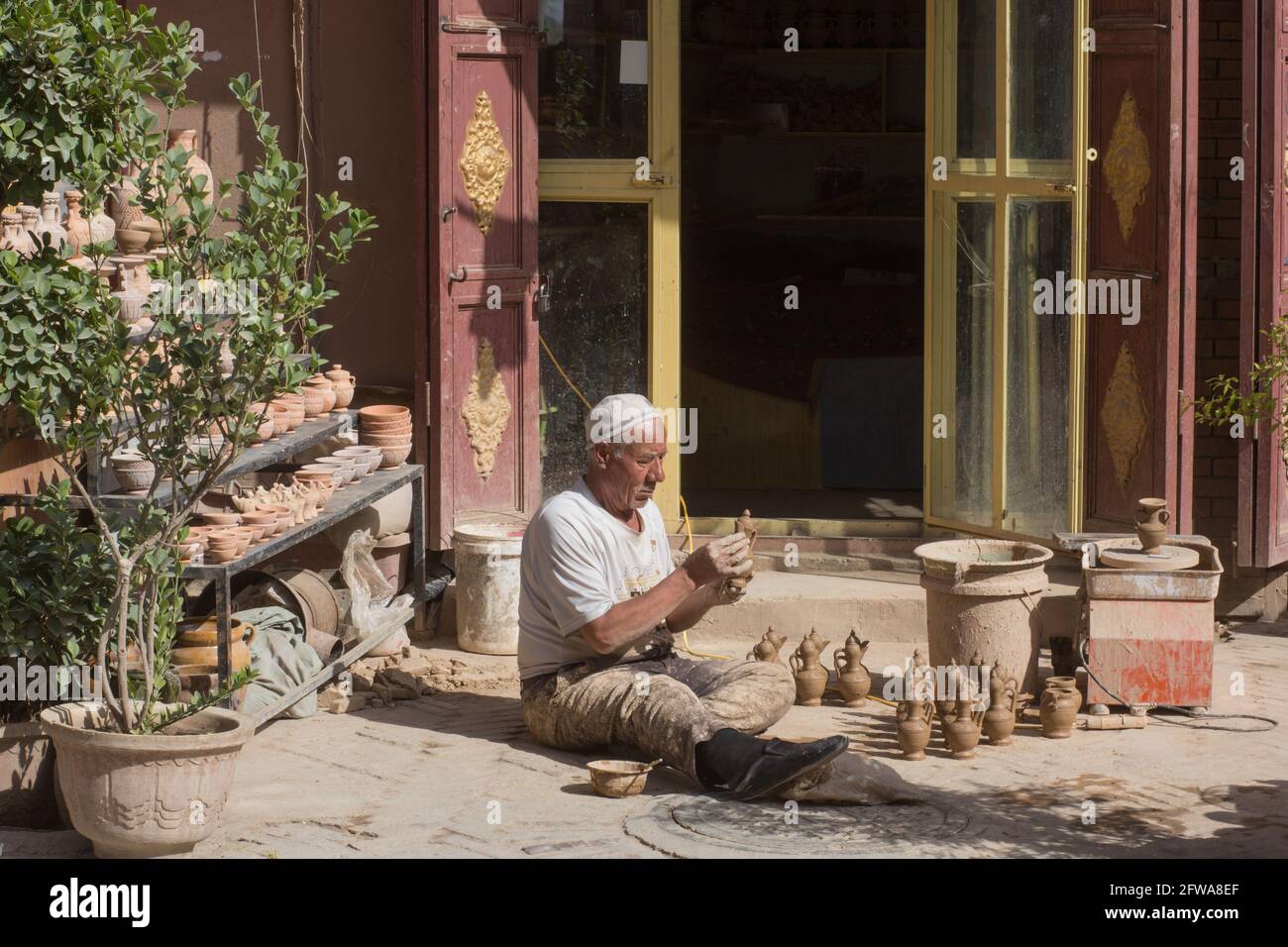 Un uomo seduto fuori della sua casa mostrando e lavorando con Clay Kashgar, Sinkiang, Repubblica popolare Cinese, 2019 Foto Stock