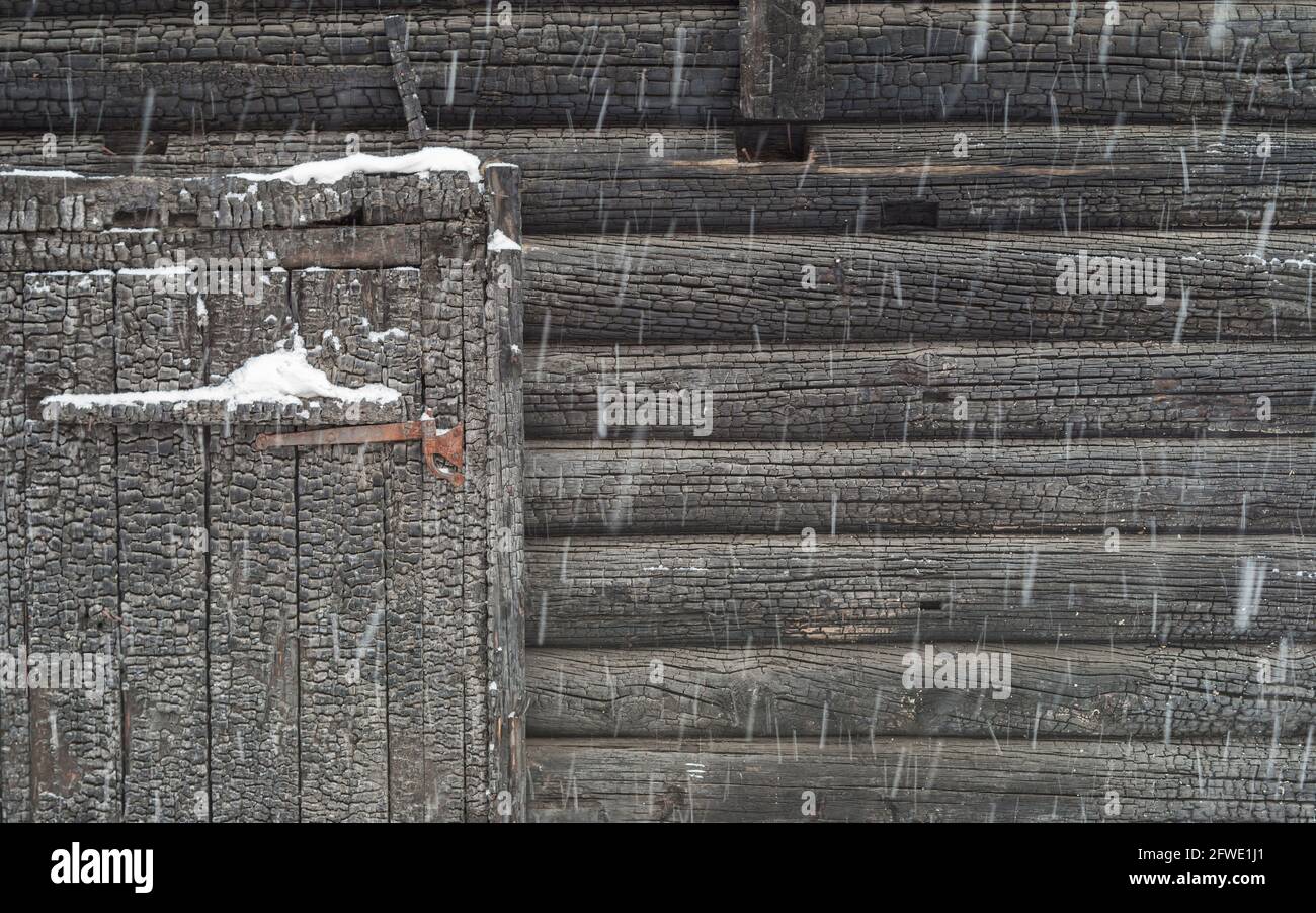 Porta a battente e un frammento della facciata di una vecchia casa bruciata durante una forte nevicata, Foto Stock