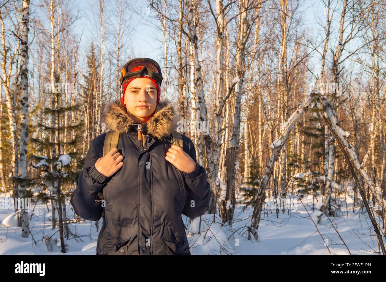Felice giovane uomo, adolescente passeggiate nella foresta invernale. Foto Stock