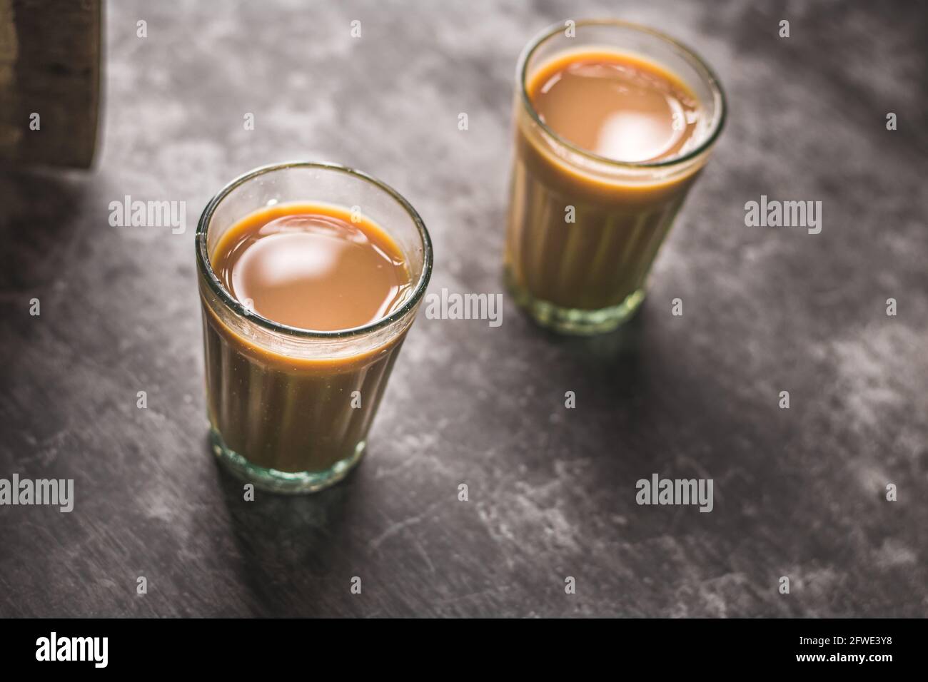 Chai indiano in tazze di vetro con bollitore di metallo e altre masala per preparare il tè. Foto Stock