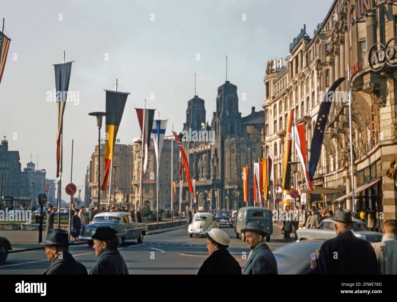 Una vista che guarda a nord a Am Hauptbahnhof al suo incrocio con Kaiserstasse, Francoforte sul meno Germania c. 1958. La gente va da e per la stazione ferroviaria centrale (situata a sinistra di questa immagine) e le bandiere di molte nazioni sono in mostra. È stata inoltre volata la bandiera blu/oro del Consiglio d'Europa (destra). Risale al 1955. Centro è la facciata del Circus-Teatro Albert Schumann che cosa era rimasto dell'edificio dopo i bombardamenti alleati nel 1944 è stato demolito nel 1960. Questa immagine proviene da un vecchio lucido a colori Kodak dilettante da 35 mm, una fotografia degli anni '50. Foto Stock