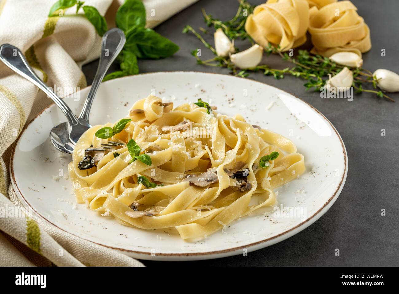 Fettuccine di pasta con funghi e prosciutto di pollo fritto in cremoso salsa di formaggio su uno sfondo di legno chiaro Foto Stock