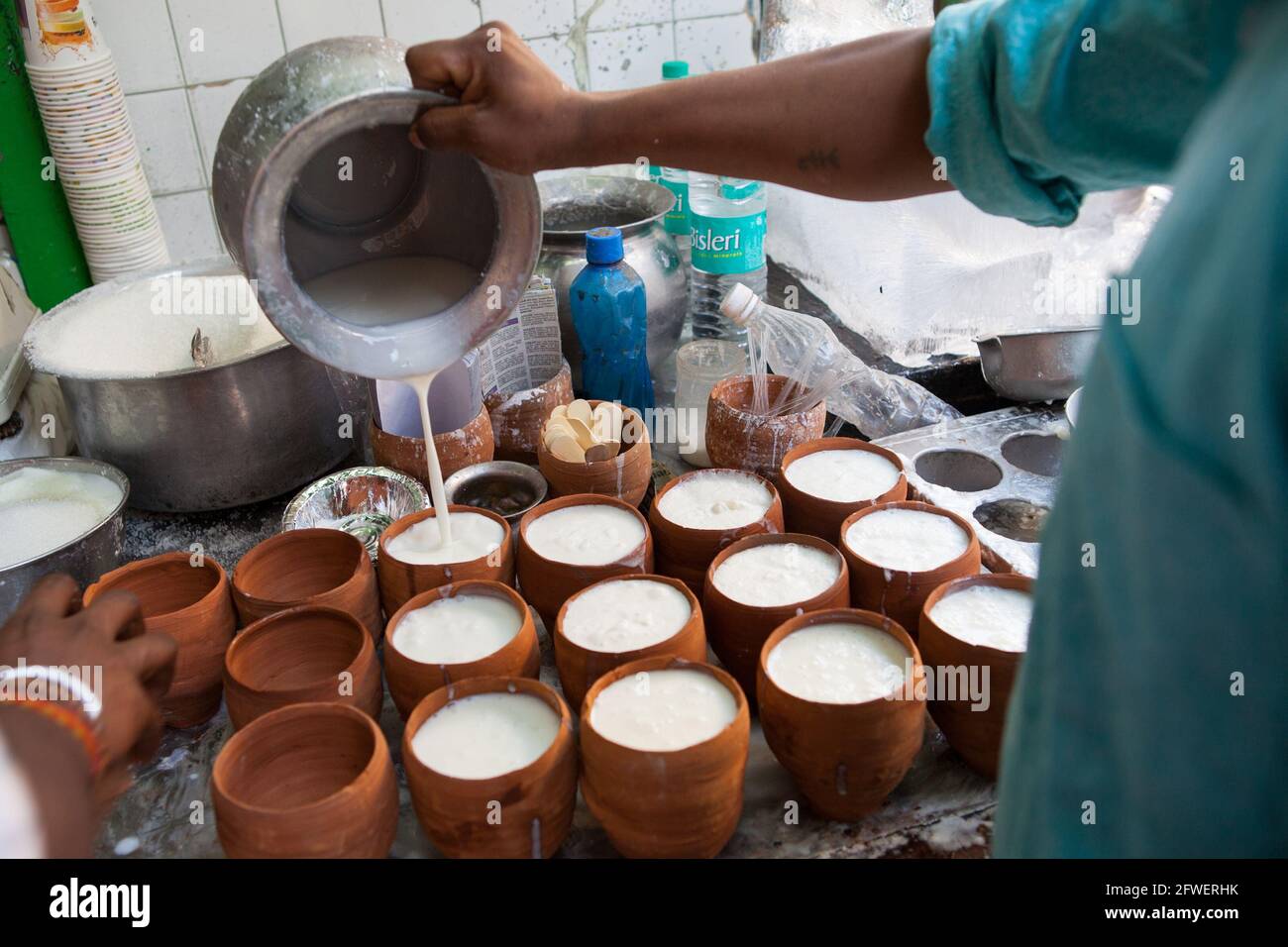 Un lavoratore riempie le pentole di lassi in un hotel gastronomico Nella città vecchia di Delhi Foto Stock