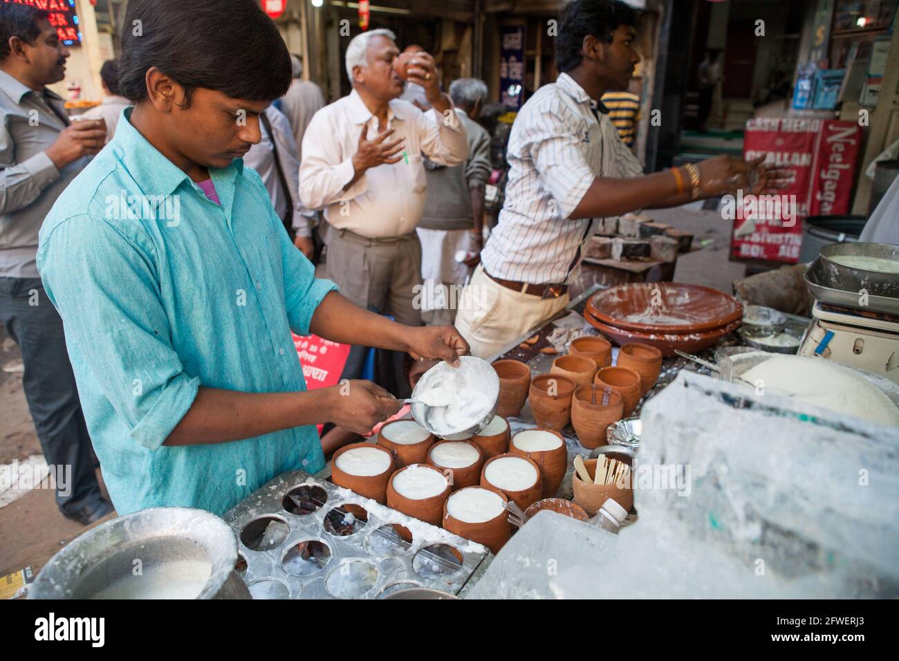 Un uomo prepara pentole di lassi in un food hotel Nella città vecchia di Delhi Foto Stock